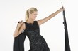 Woman holds up black dress, choosing what to wear