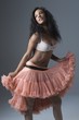 Woman stands in lace bra and peach coloured petticoat skirt