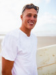 Portrait of a handsome young surfer at the sea shore