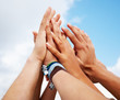 Human hands raised together against the blue sky