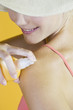 A Young Woman Spraying Suntan Lotion On Her Shoulder