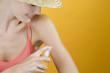 A Young Woman Spraying Suntan Lotion On Her Arm