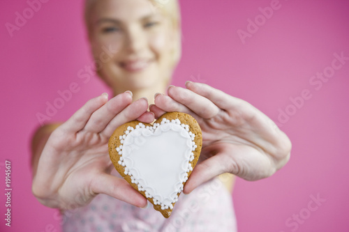 Photo: A Young Woman Holding Out A Heart Shaped Biscuit A Young Woman Holding Out A Heart Shaped Biscuit