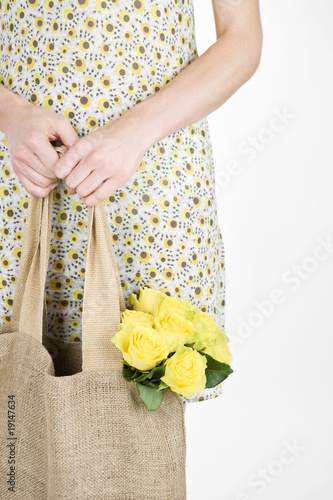 Photo: A Young Woman Carrying A Bunch Of Yellow Roses In A Shopping Bag A Young Woman Carrying A Bunch Of Yellow Roses In A Shopping Bag
