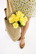 A Young Woman Carrying A Bunch Of Yellow Roses In A Shopping Bag