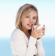 Cute female having a cup of coffee against the blue sky