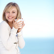 Pretty female smiling with a cup of coffee against the blue sky