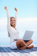 Cute female with hands raised using on a laptop outdoors