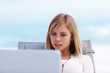 Cute blond using a laptop outdoors