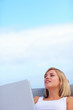 Cute young female using a laptop against the blue sky