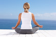 Rear view of a female meditating on a porch against the sky
