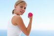 Happy fit woman with a pink dumbbell , exercising outside