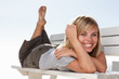 Cute happy woman lying on a wooden bench