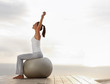 Fitness woman exercising on a ball outdoors