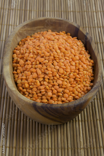 Photo: Wooden bowl with uncooked red lentils. Wooden bowl with uncooked red lentils.