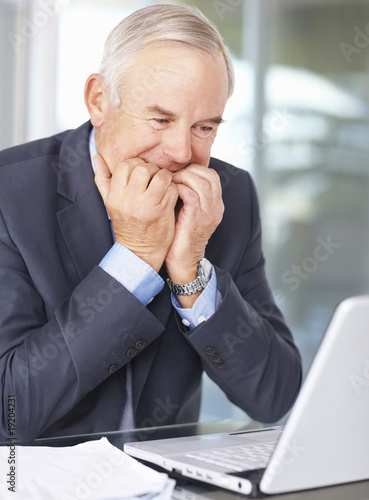 Photo: Biting nails - Senior business man looking at the laptop at work Biting nails - Senior business man looking at the laptop at work