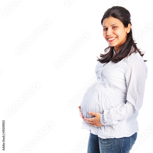 Photo: Young pregnant woman holding her stomach smiling Young pregnant woman holding her stomach smiling