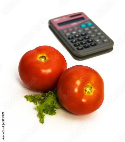 Photo: two tomatoes in front, calculator blurred in background two tomatoes in front, calculator blurred in background