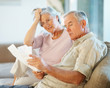 Elderly man with his wife going through documents on couch