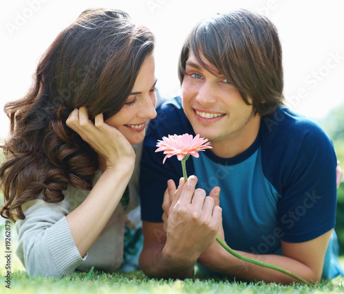 Photo: Cute young lying on the grass with a fresh flower Cute young lying on the grass with a fresh flower