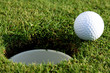 Golf ball on lip of cup at green