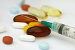 Multicolored pills and syringe on a white background