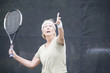 Senior woman serving at tennis