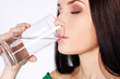 Beautiful young girl drinks water from glass