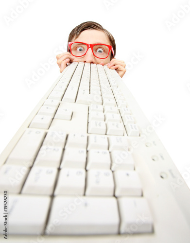 Photo: Funny guy hiding behind a computer keyboard Funny guy hiding behind a computer keyboard