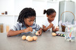 Concentrated Afro-american siblings painting eggs