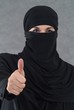Eine muslimische Frau im Burka zeigt Finger nach oben.