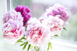 Vase of peony blooms in window