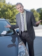Frustrated businessman shrugging at parking ticket on windshield
