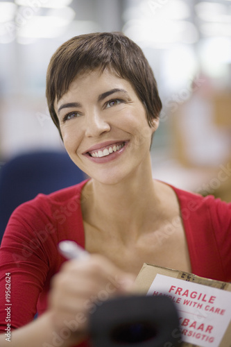 Photo: Businesswoman marking fragile box with marker Businesswoman marking fragile box with marker