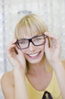 Woman trying on glasses in optometrist?s shop