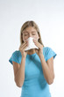 Young woman blowing her nose with kleenex
