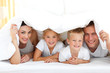 Foto: Young family playing together on a bed Young family playing together on a bed