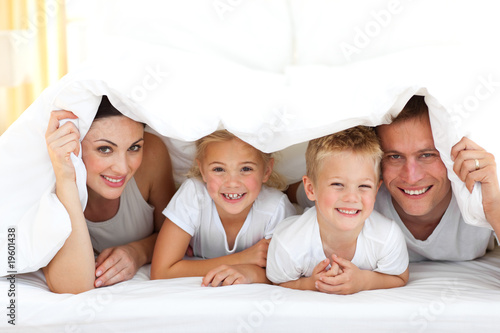 Foto: Young family playing together on a bed Young family playing together on a bed