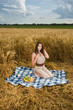 Beautiful slavonic girl on picnic in wheat field with fruits