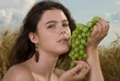 Beautiful slavonic girl on picnic in wheat field with grapes