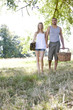 A young couple holding hands, carrying a picnic basket