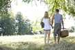 A young couple holding hands, carrying a picnic basket