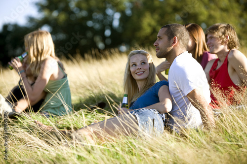 Photo: A group of young people sitting in a park, drinking beers A group of young people sitting in a park, drinking beers