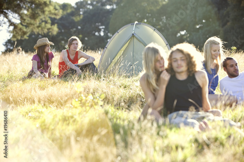 Photo: Three young couples sitting in a field near a tent Three young couples sitting in a field near a tent