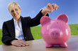 Woman Putting Coin Into Pink Piggy Bank In Green Field