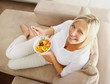 Top view of a relaxed mature woman on couch eating fruit salad