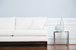 White Sofa and Glass End Table Against Blue Wall