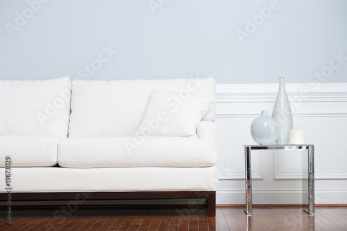 Photo: White Sofa and Glass End Table Against Blue Wall White Sofa and Glass End Table Against Blue Wall