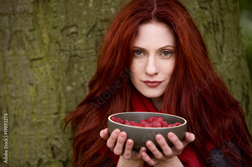 Photo: A young woman holding a bowl of raspberries A young woman holding a bowl of raspberries