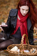 A young woman looking in picnic basket, holding a glass of wine